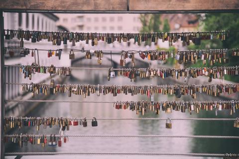 Dozens of padlocks attached to a bridge.