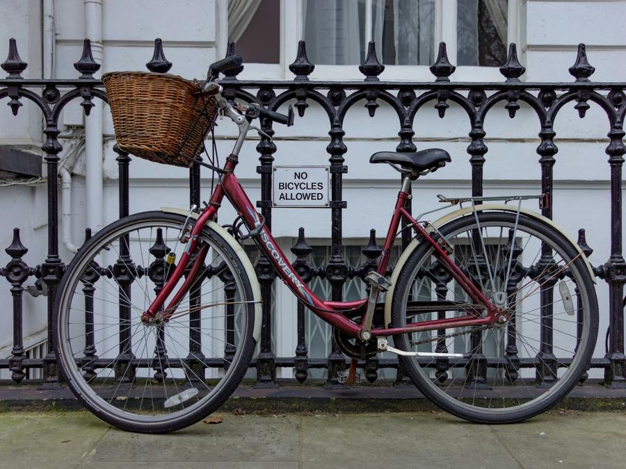 A bicycle sitting in front of a "no bicycles" sign.
