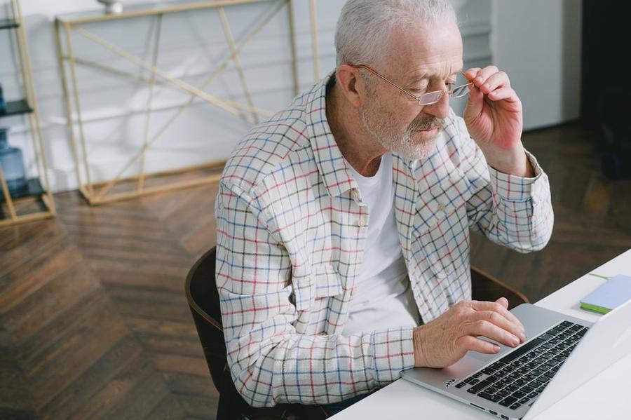 Elderly man looking at a computer through his glasses