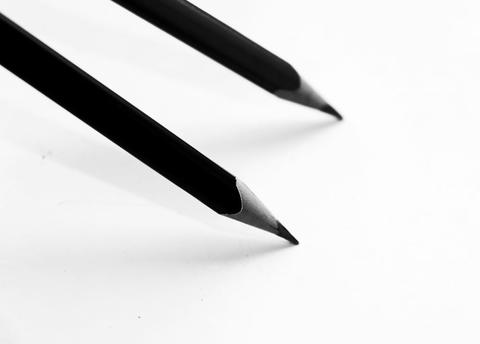 Two parallel pencils poised to write on a plain white background.
