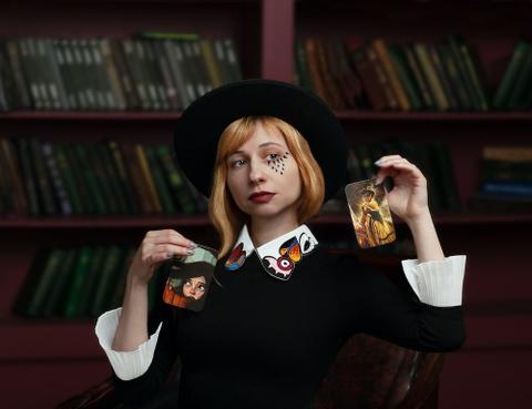 Woman holding cards in front of a bookshelf