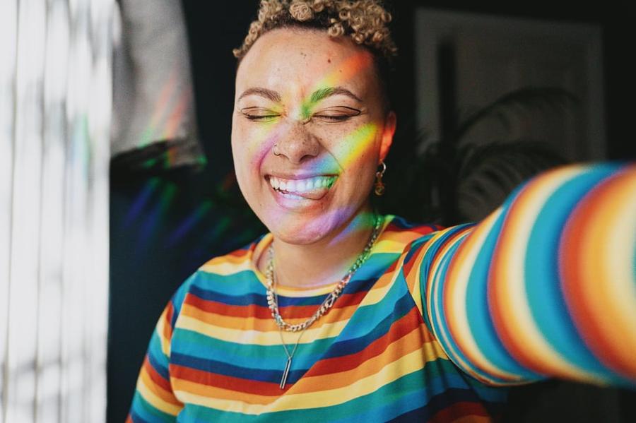 Person in a multi-colored sweater making a funny face as they take a selfie.