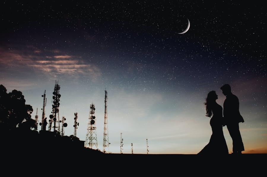 Silhouette of lovers embracing against a moonlit sky.