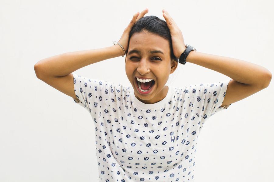 A stressed-looking person holds their hands on either side of their head, yelling.