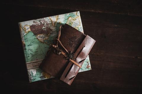A closed leatherbound journal on top of a folded map.