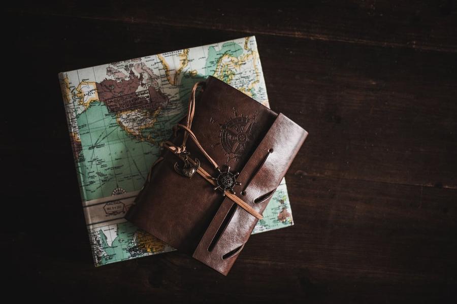 A closed leatherbound journal on top of a folded map.