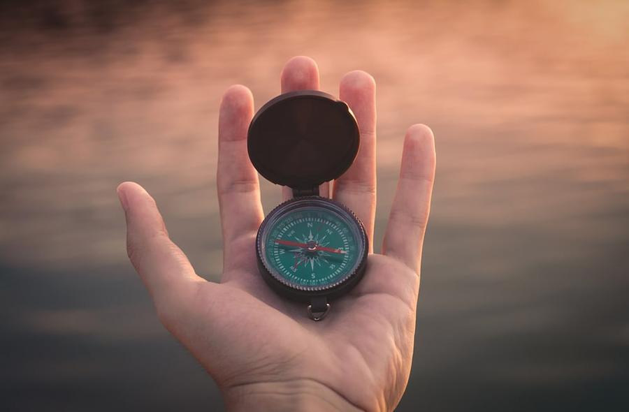 Hand holding a black and green compass.