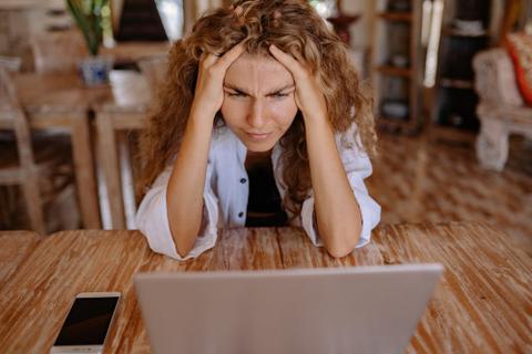 A stressed-looking person stares at a computer screen.