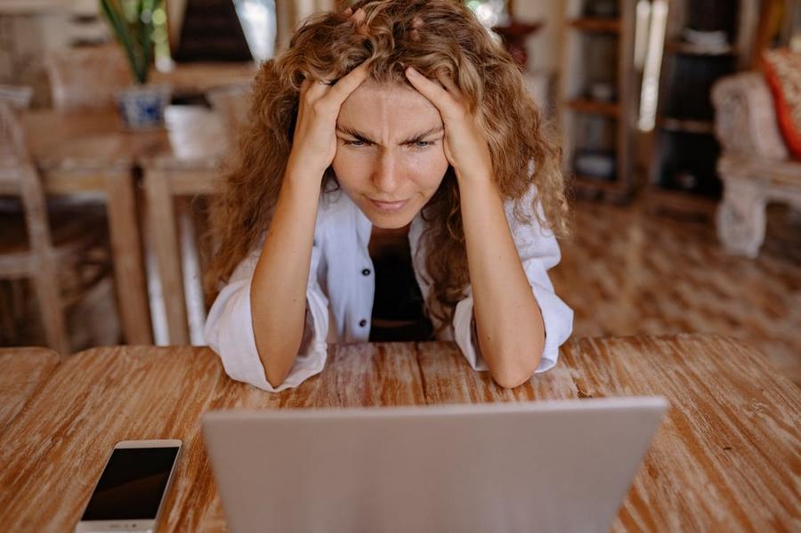 A stressed-looking person stares at a computer screen.