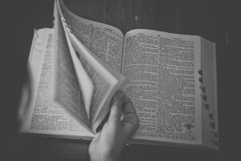 A hand flips through a dictionary.