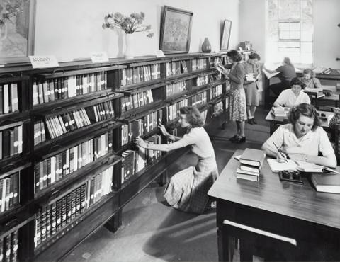 A mid-century photograph of women researching in a library.