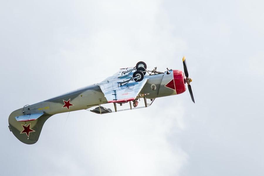 Red and white airplane flying upside down.
