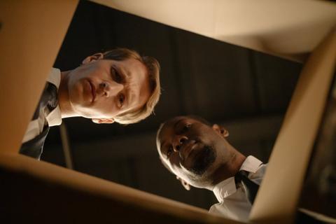 Two detectives look into a cardboard box.
