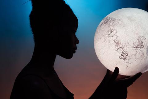 Silhouette of a person holding the moon.