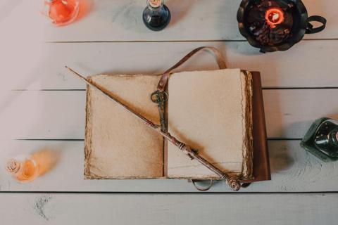 A wand sits on an open leather-bound spell book.