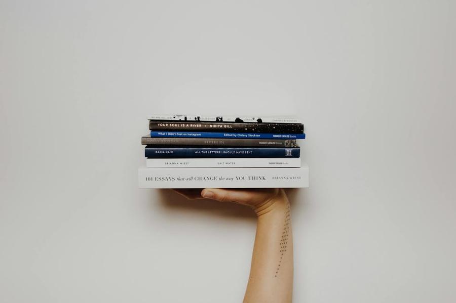 A hand holds a stack of books like a serving tray.