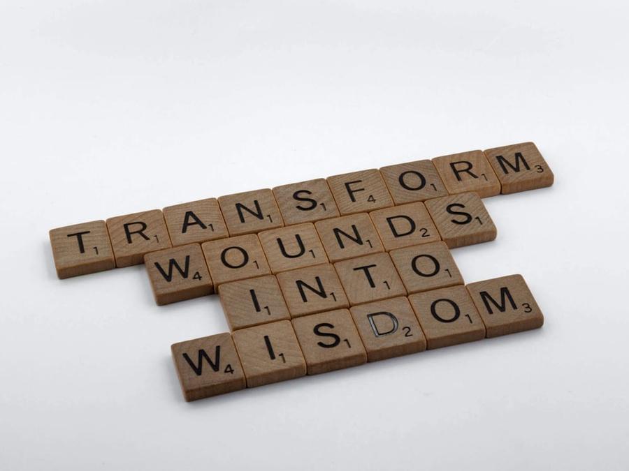 Scrabble tiles that read "Transform wounds into wisdom."