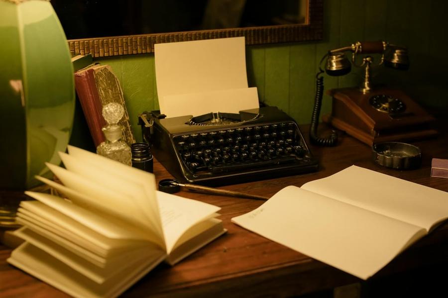 Open notebooks sit on a desk beside a vintage typewriter.