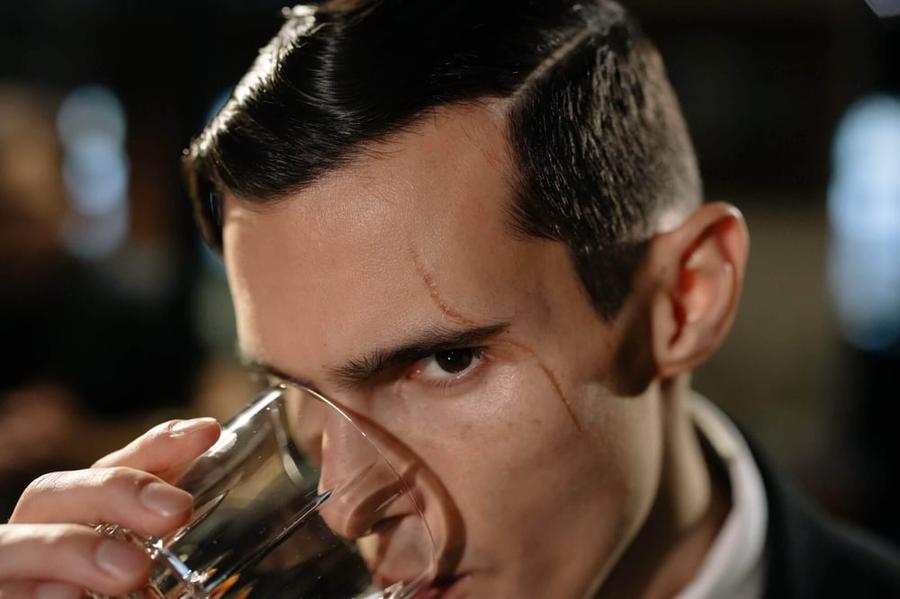 A man sipping a drink with a suspicious look.