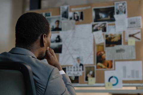 A detective stares at an investigation board.