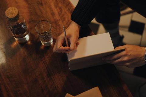 A hand signs a book.