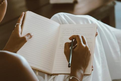 Hands writing in a journal.
