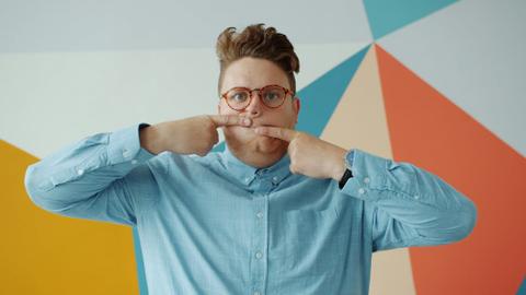 A person makes a funny face, using one hand to pull their top lip one way and the other to pull their bottom lip the other way.