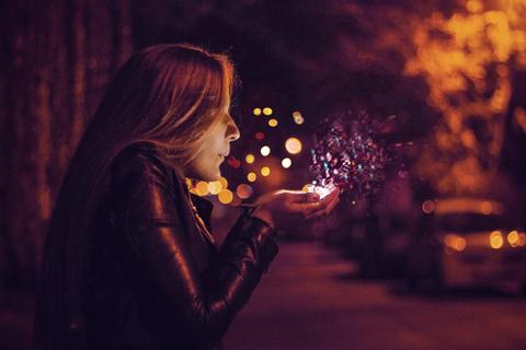 A woman blowing into her cupped hands, magical glitter floating outwards.