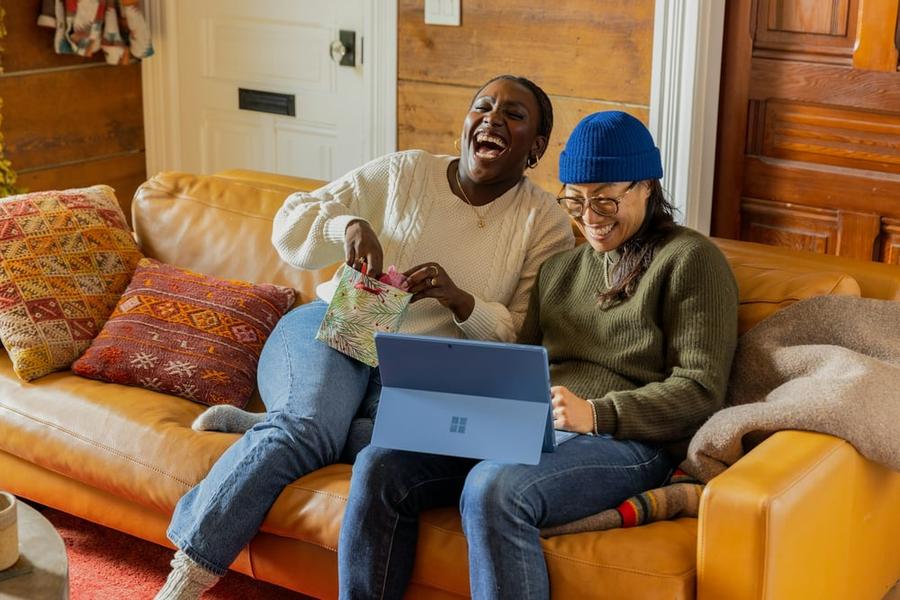 Two people laugh at a computer screen.
