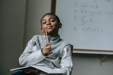 A kid at a desk looks thoughtful.
