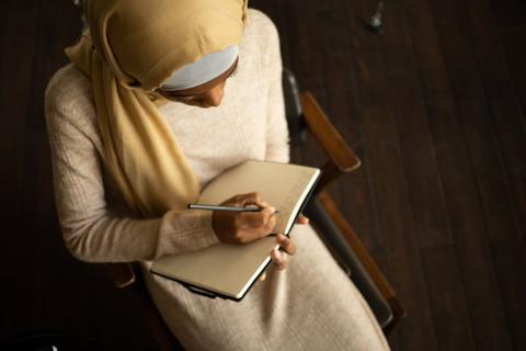 A person sits and writes in a notebook.