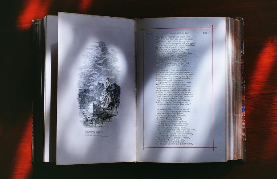 Sunlight falls across a narrative poem on the pages of an open book.