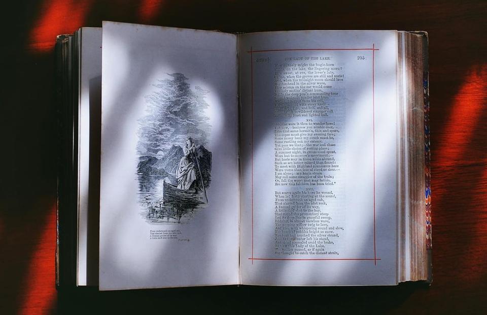 Sunlight falls across a narrative poem on the pages of an open book.