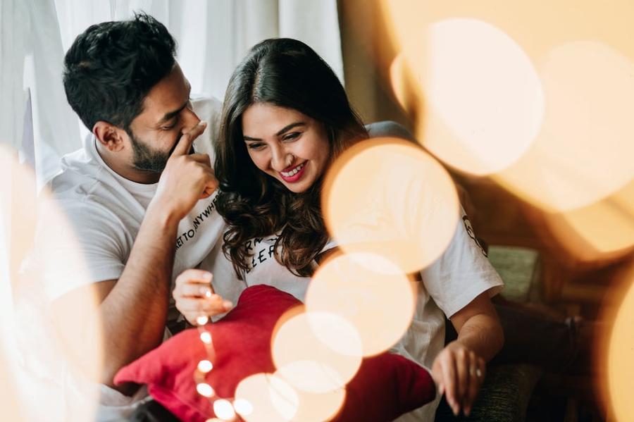 A smiling couple in a room with string lights.