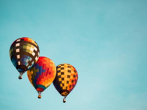 Three colorful hot air balloons floating against a blue sky.