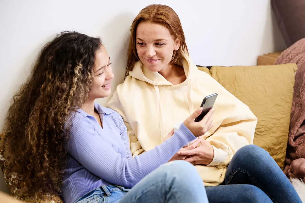 Two women in a couch discussing an app