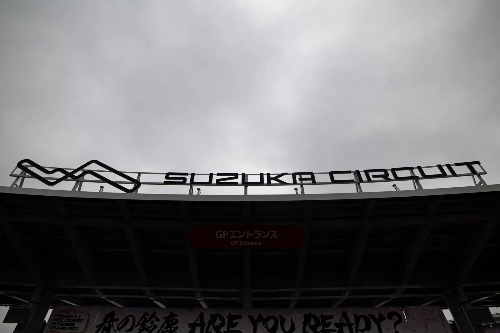 The Suzuka Circuit sign under a grey sky.