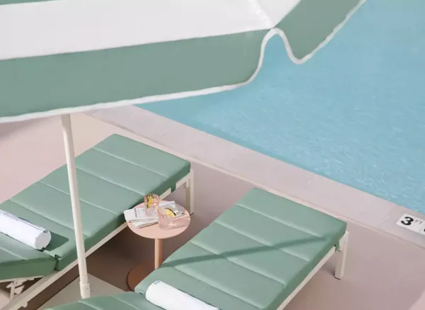 Loungers under a green and white striped parasol on the pink deck beside the Park MGM pool.