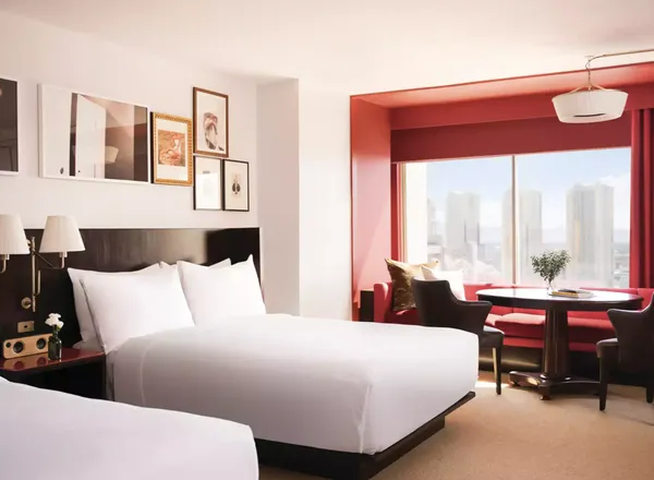 A Park MGM guest room with two beds and a red window nook looking out over the Strip.