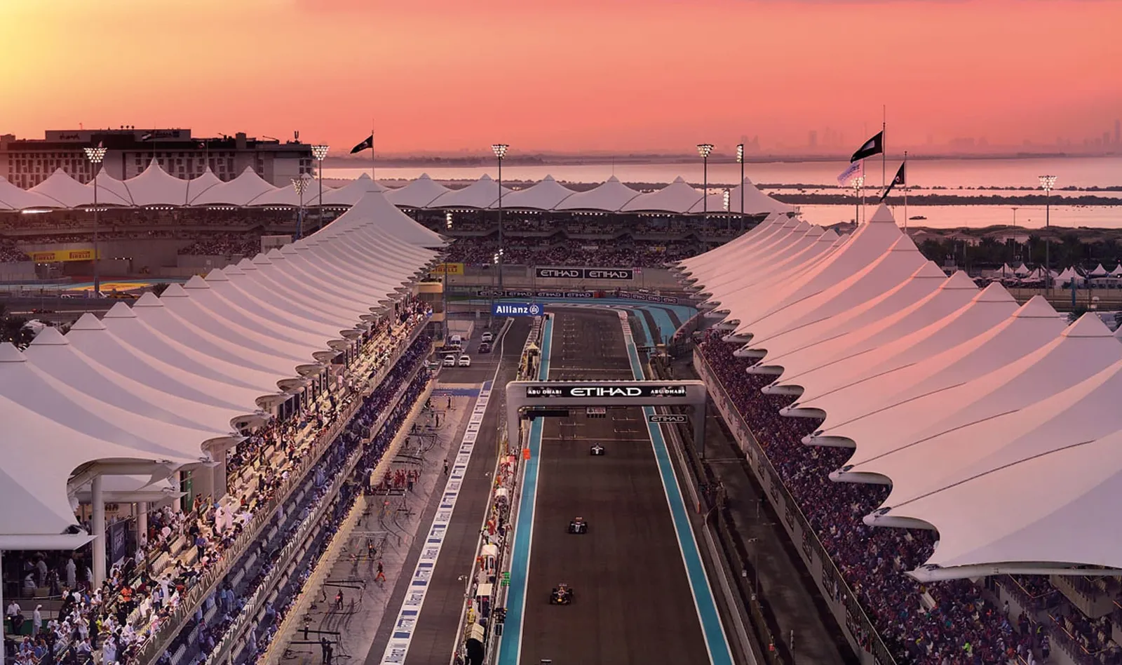 The Yas Marina pit straight at dusk, grandstands full.