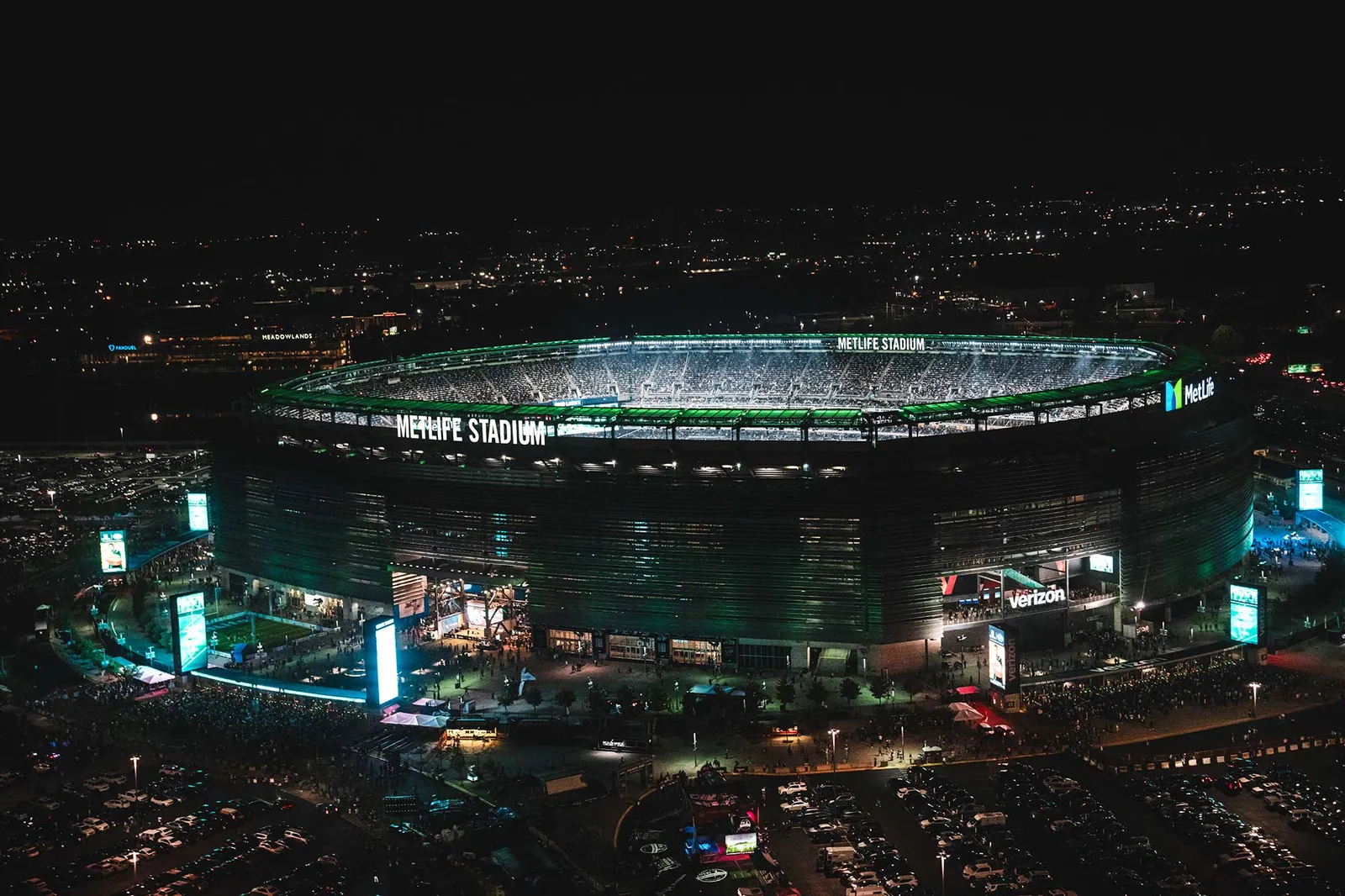 MetLife Stadium lit green at night, from the air.