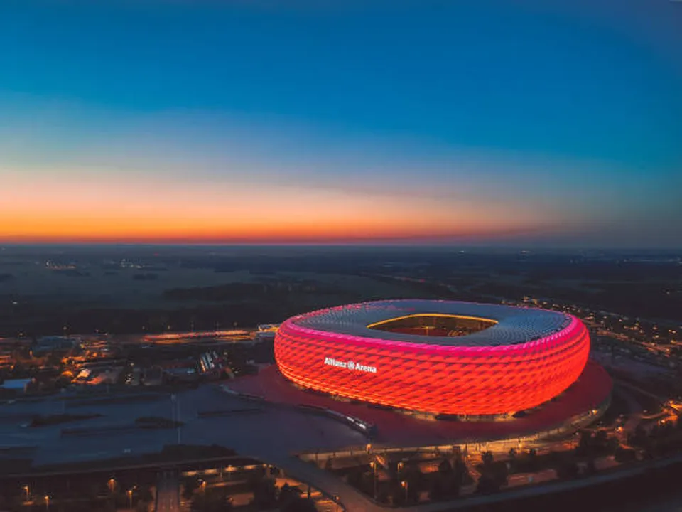 The Allianz Arena glowing red at dusk.