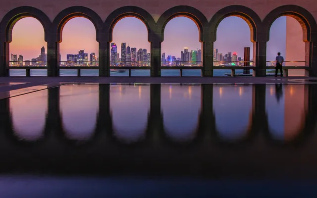 The Doha skyline at night through the arches.