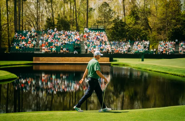 A player walks the 16th at Augusta National with the grandstand behind.