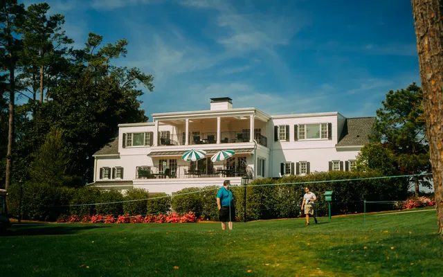 The Augusta National clubhouse from the lawn, umbrellas out on the balcony.