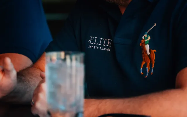 An Elite Sports Travel team member in branded polo talking with a client