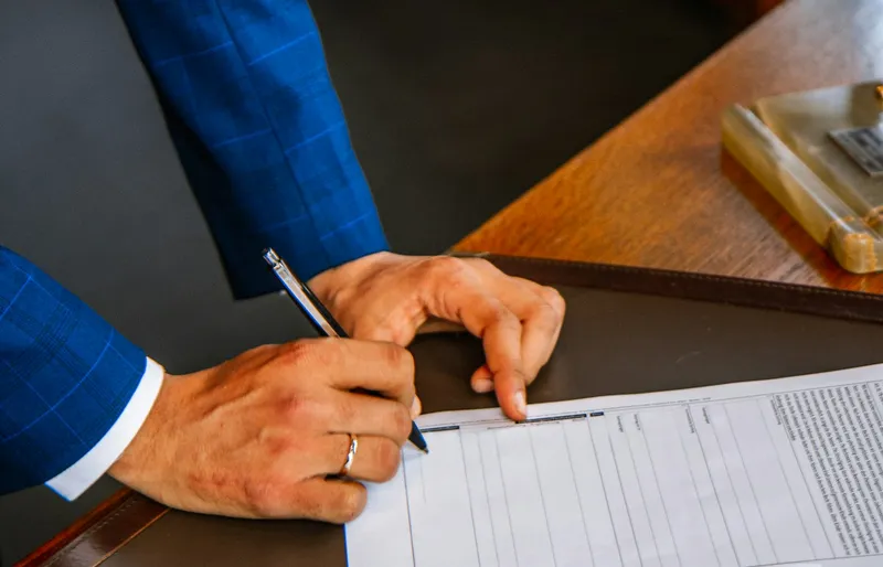 Person signing a form with a pen