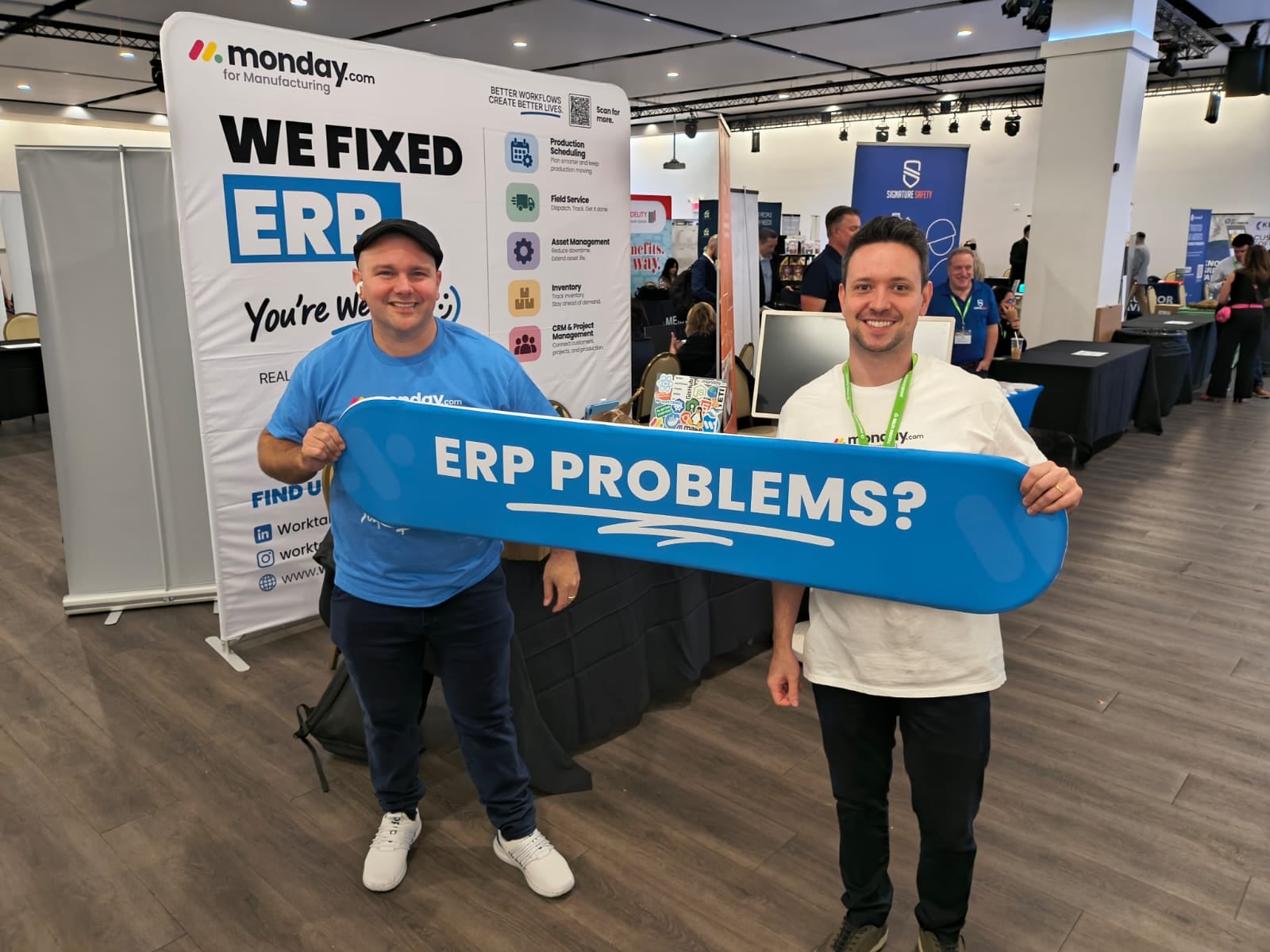 Two of the Worktables team holding the “ERP problems?” banner at the monday.com for Manufacturing booth, MFG Day 2026 with NJMEP