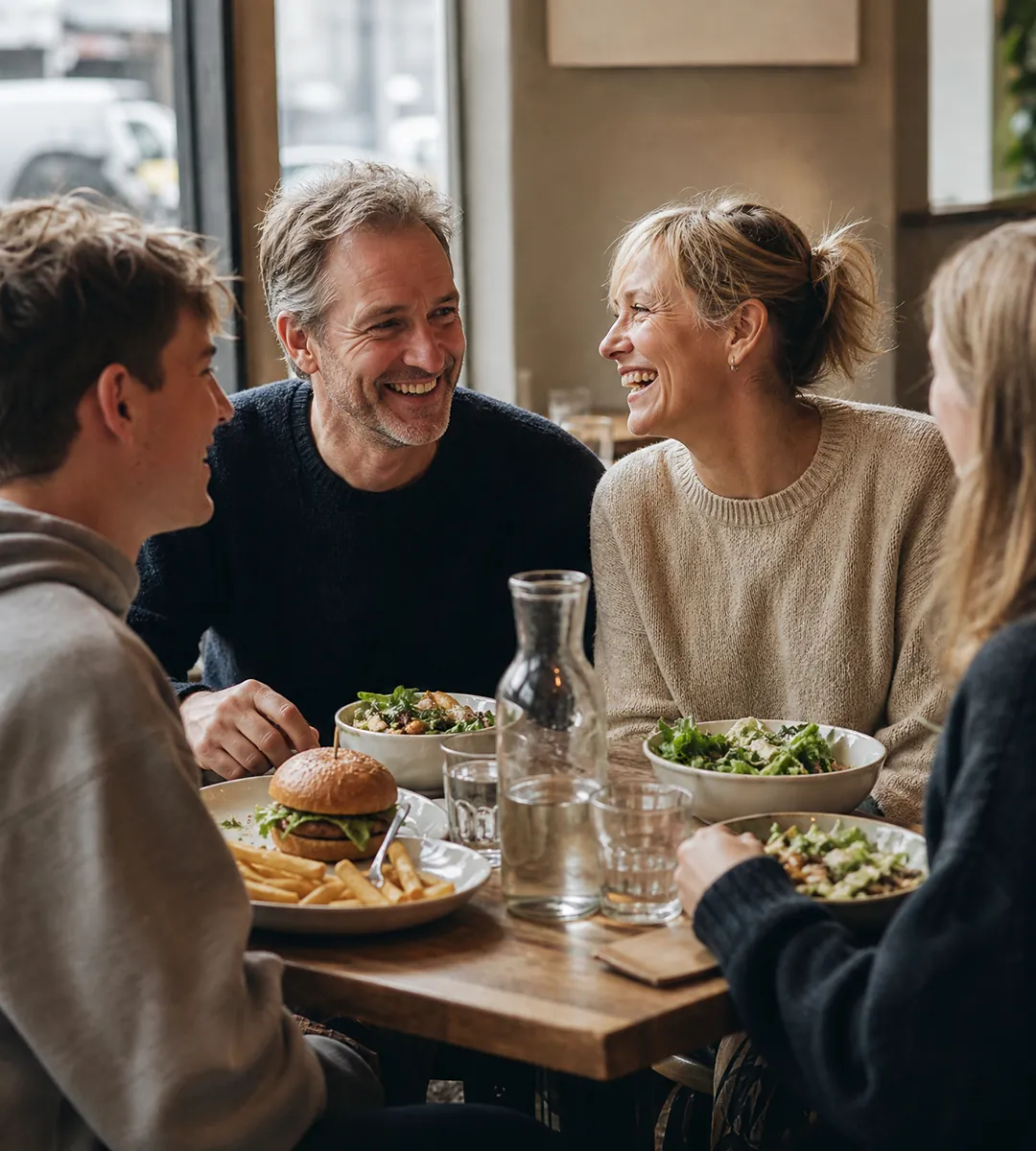 A family sharing a meal together around a restaurant table, talking and laughing.