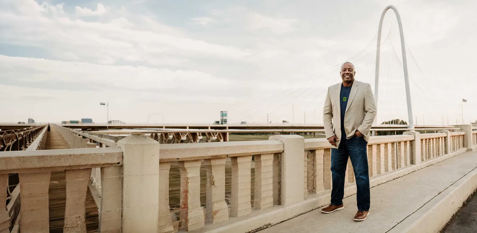 Joe Beard standing on a bridge walkway, a cable-stayed bridge behind him